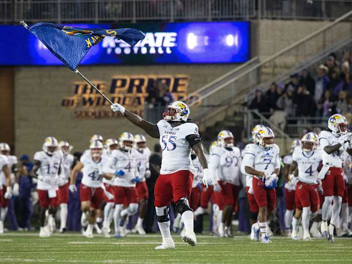 A Kansas football player waves a Jayhawks flag